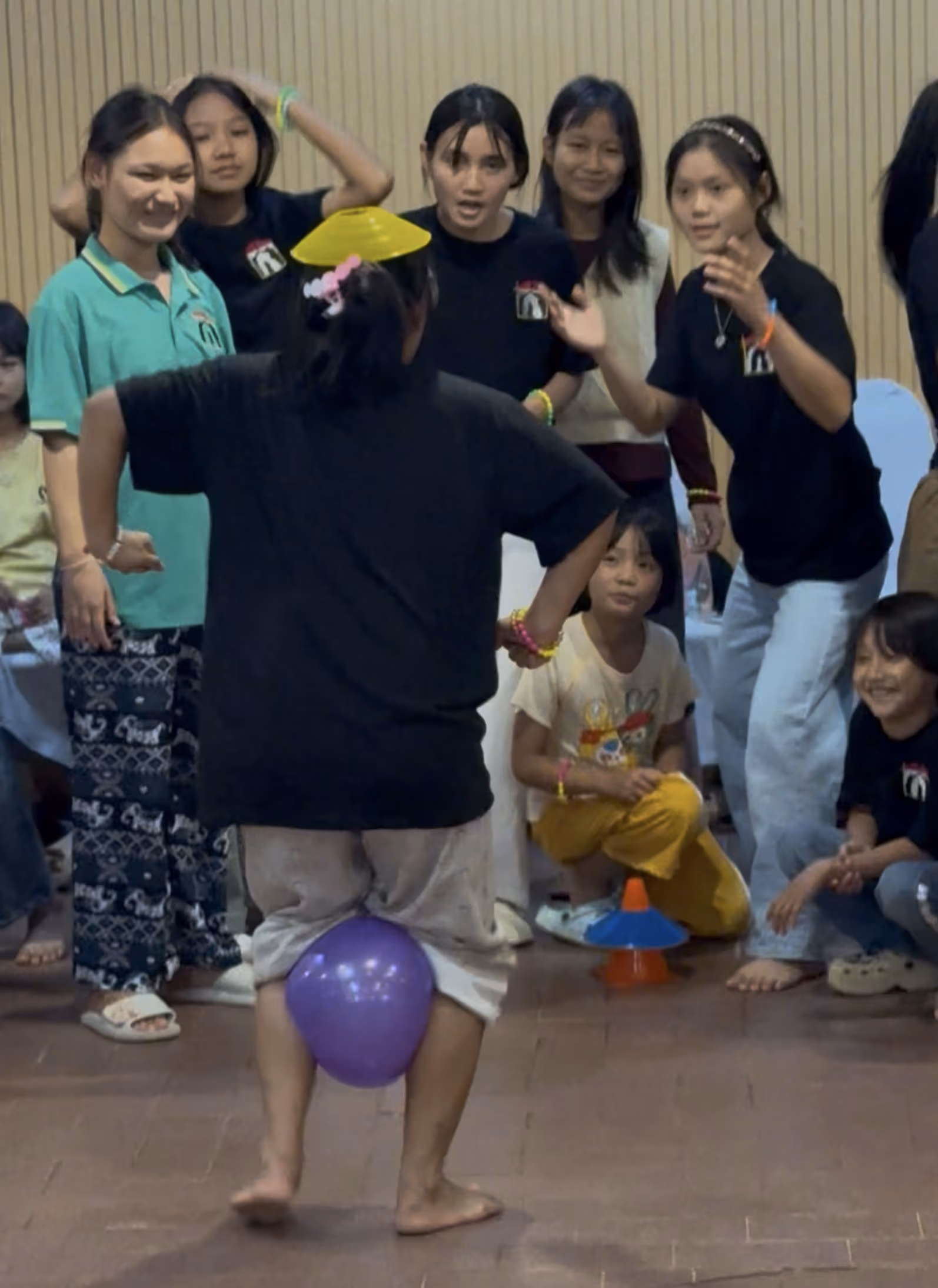 A Faith House girl walking with a cone on her head and a balloon between her legs